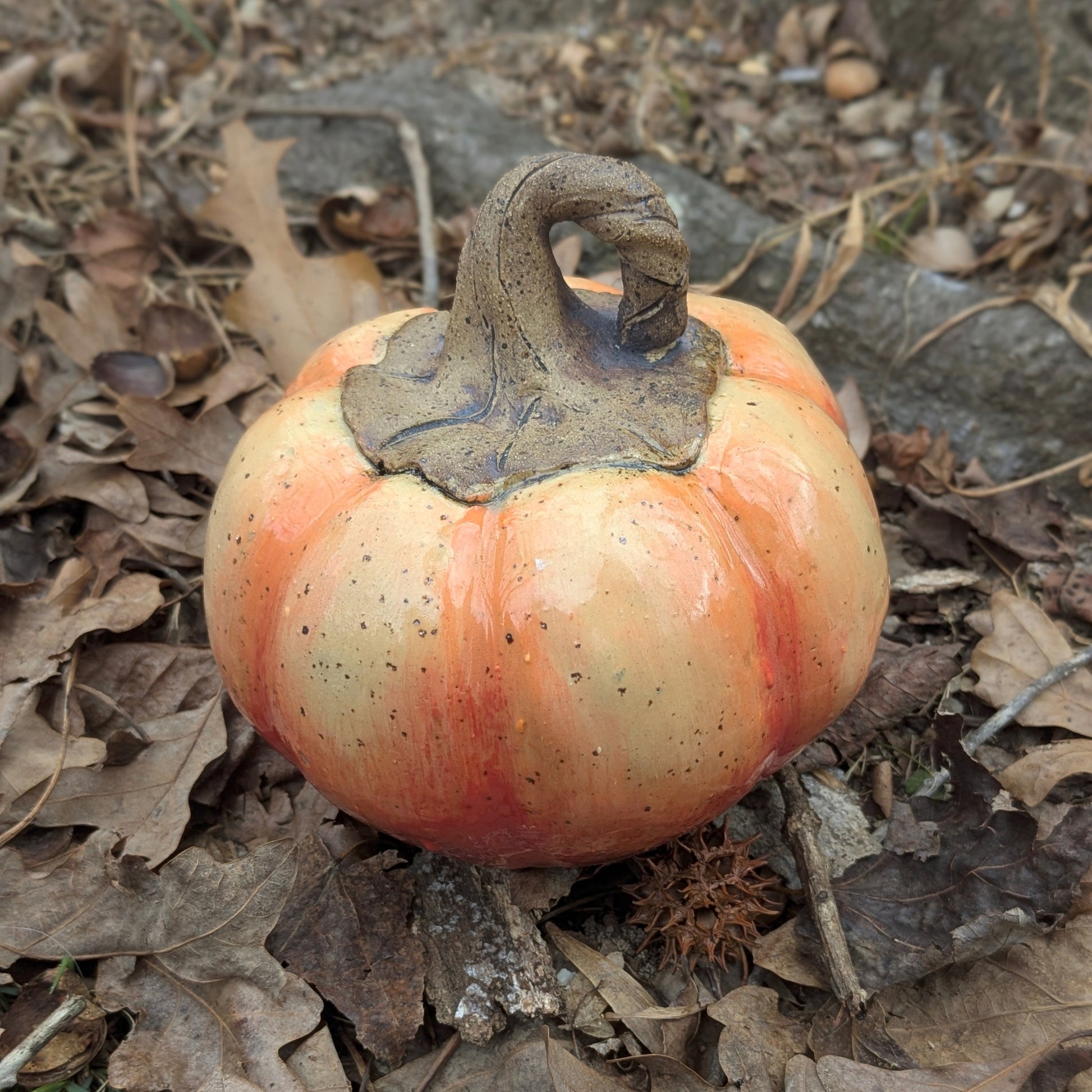 Small ceramic pumpkin on dry leaves