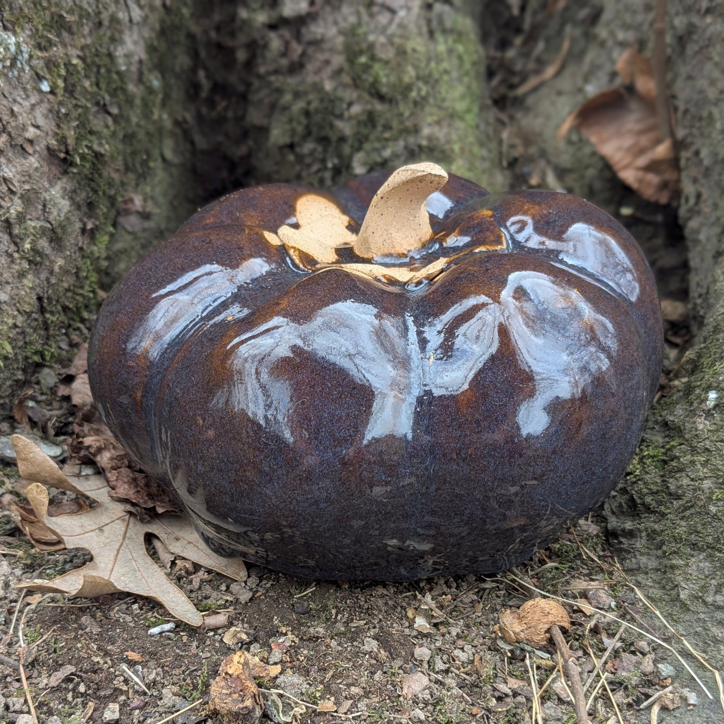 Small ceramic pumpkin on dry leaves