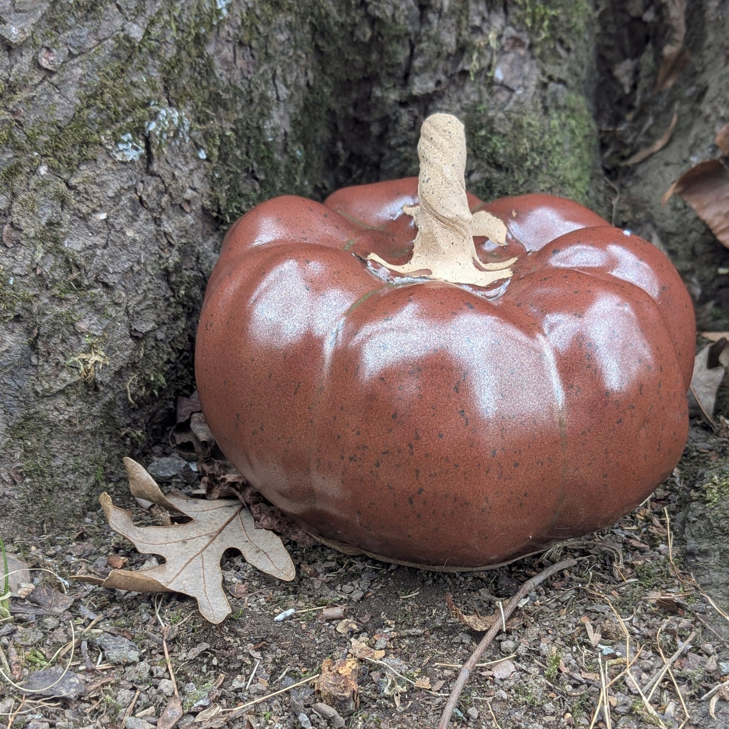 Small ceramic pumpkin on dry leaves