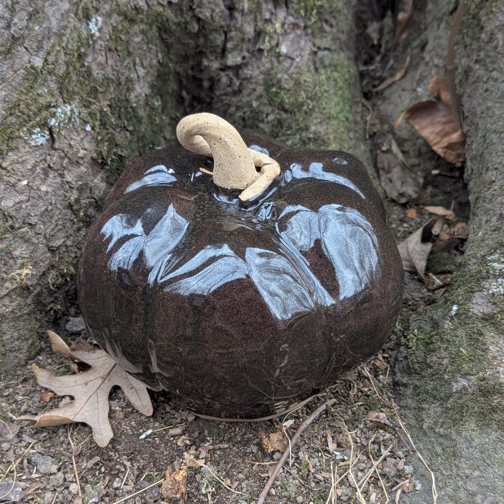 Small ceramic pumpkin on dry leaves