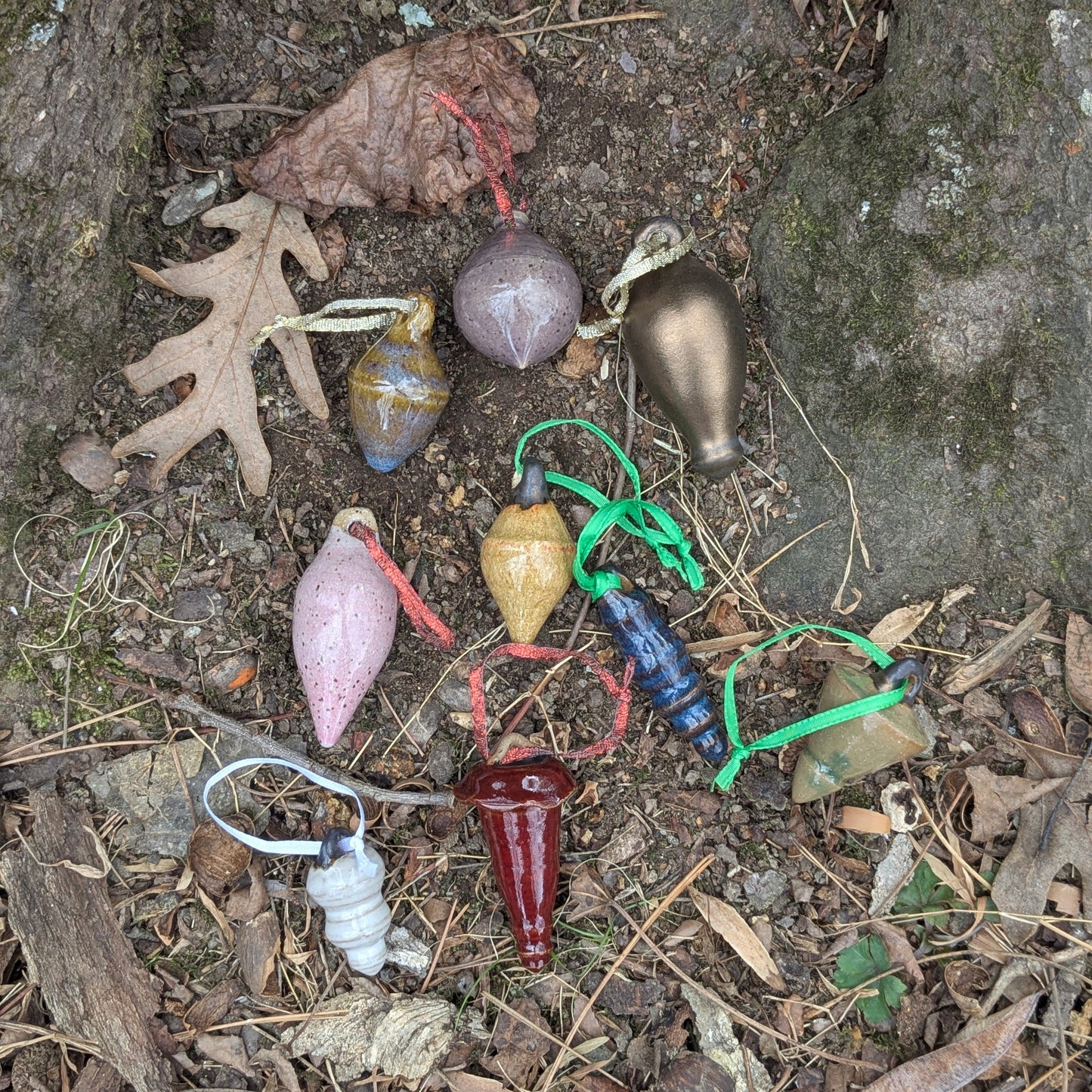 Colorful ceramic ornaments on a natural stone surface with leaves and twigs.