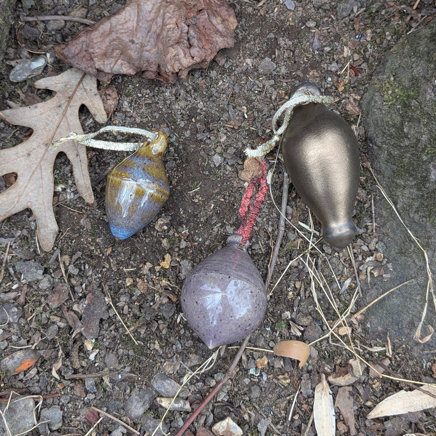 Colorful ceramic ornaments on a natural stone surface with leaves and twigs.