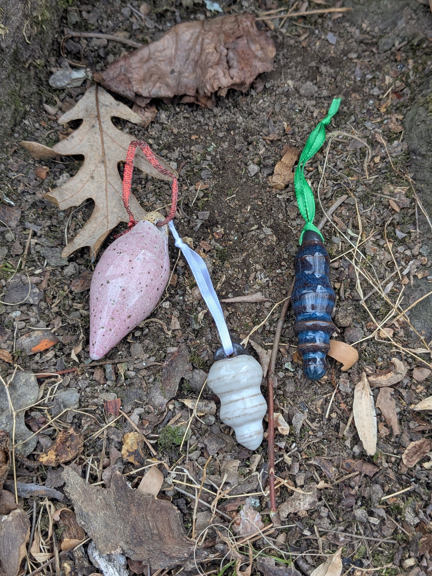 Colorful ceramic ornaments on a natural stone surface with leaves and twigs.