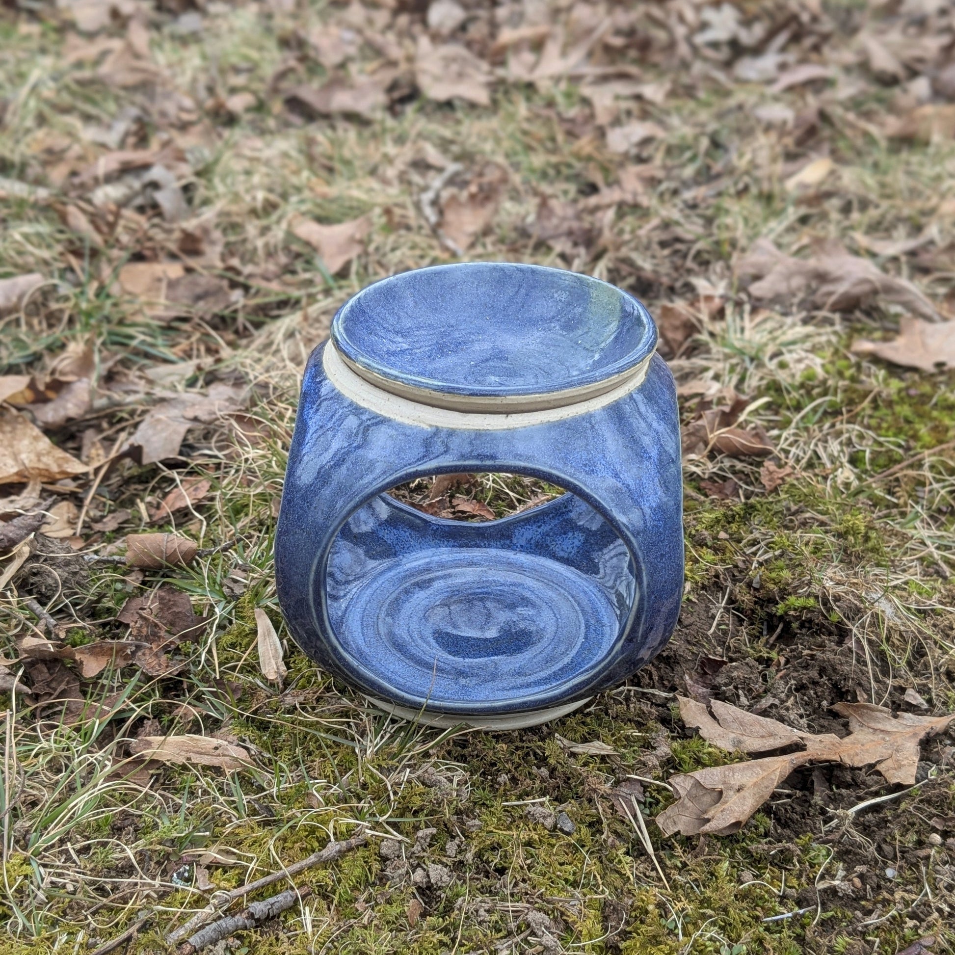 Blue ceramic lantern on a grassy ground with leaves