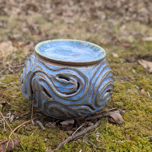 Blue ceramic pot with swirling design on a mossy ground