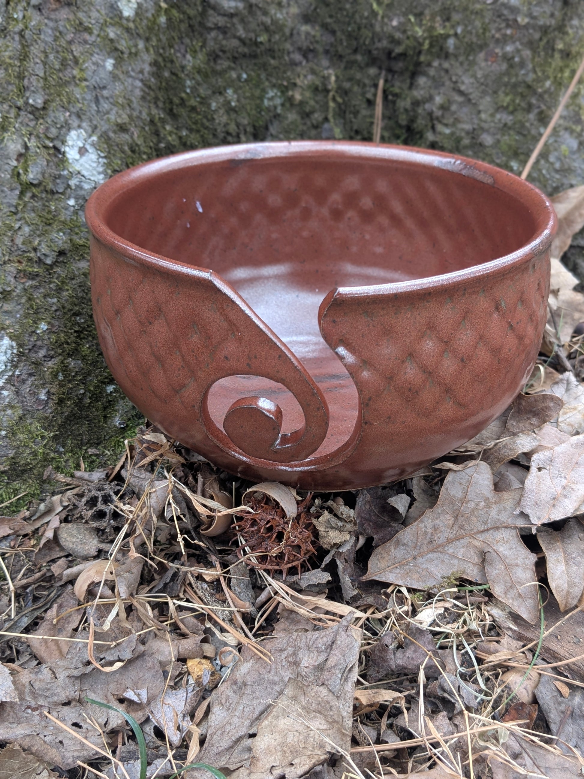 Red ceramic yarn bowl with a unique design on a natural background