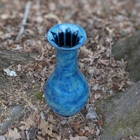 Blue ceramic vase on a ground covered with dry leaves